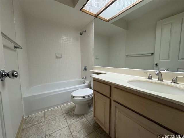 full bathroom featuring tiled shower / bath, a skylight, vanity, and toilet