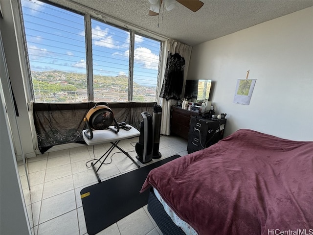 tiled bedroom featuring a mountain view, a textured ceiling, and ceiling fan