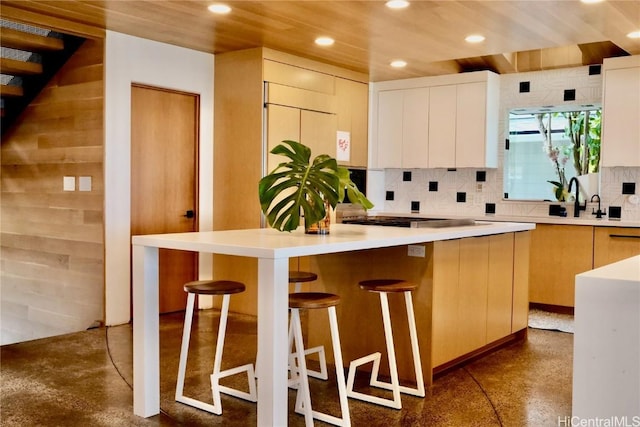 kitchen featuring sink, a center island, stainless steel gas cooktop, a kitchen breakfast bar, and wood ceiling