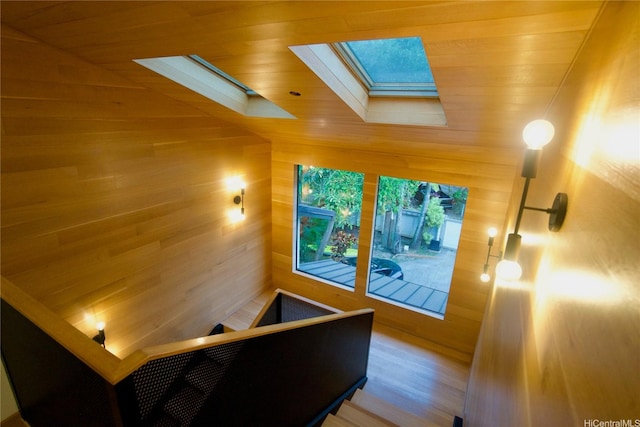 stairs featuring wood ceiling, wooden walls, and a skylight