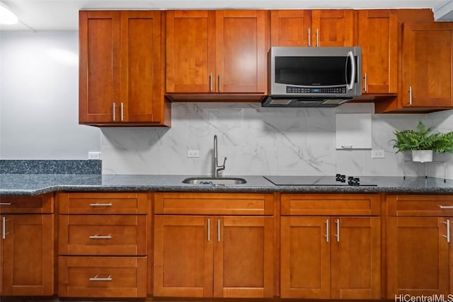 kitchen with sink, dark stone counters, black electric cooktop, and decorative backsplash