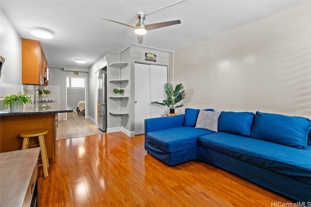 living room with sink, light hardwood / wood-style flooring, and ceiling fan