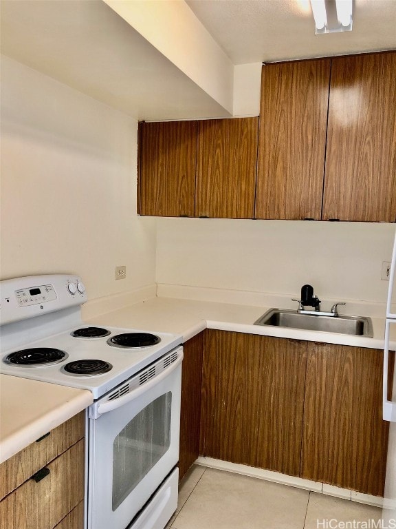 kitchen featuring white range with electric cooktop, light tile patterned floors, and sink