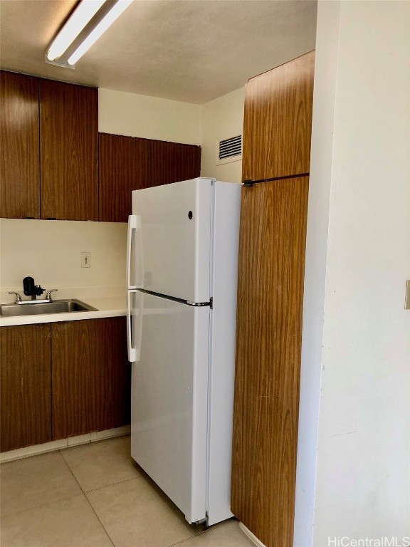 kitchen with white fridge, light tile patterned floors, and sink