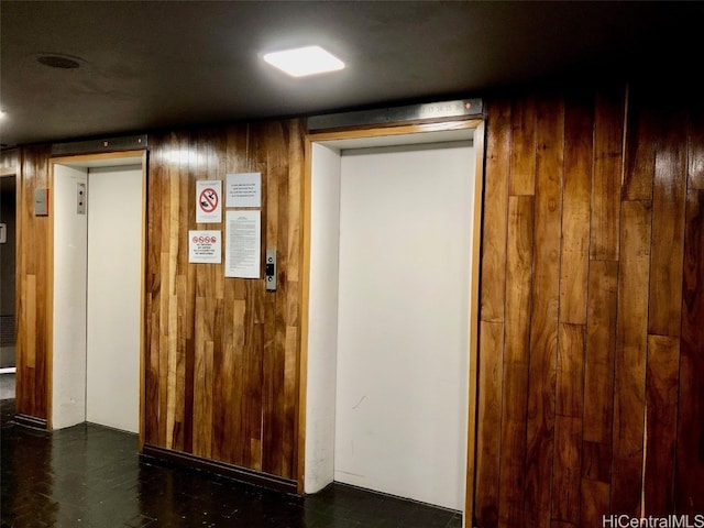 hallway with elevator and wood walls