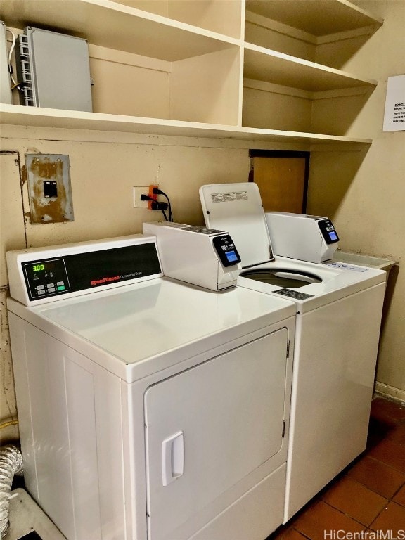 clothes washing area featuring dark tile patterned flooring and washer and clothes dryer