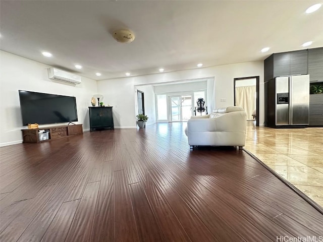 unfurnished living room featuring an AC wall unit and hardwood / wood-style floors