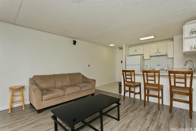 living room featuring sink, light hardwood / wood-style floors, and a textured ceiling