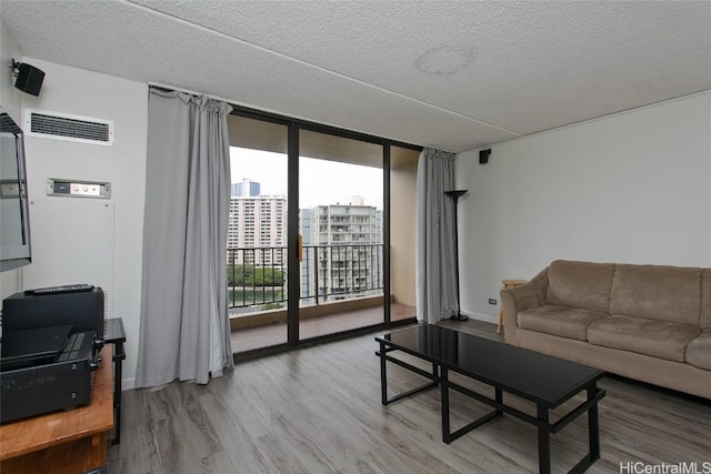 living room featuring hardwood / wood-style floors, a textured ceiling, and a wall of windows