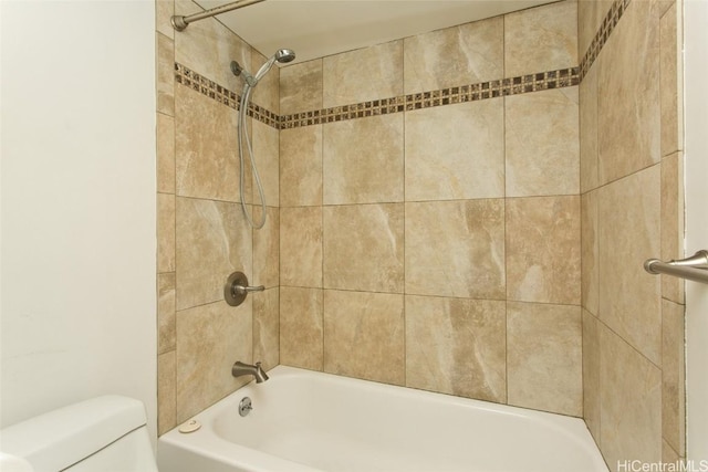 bathroom featuring tiled shower / bath and toilet