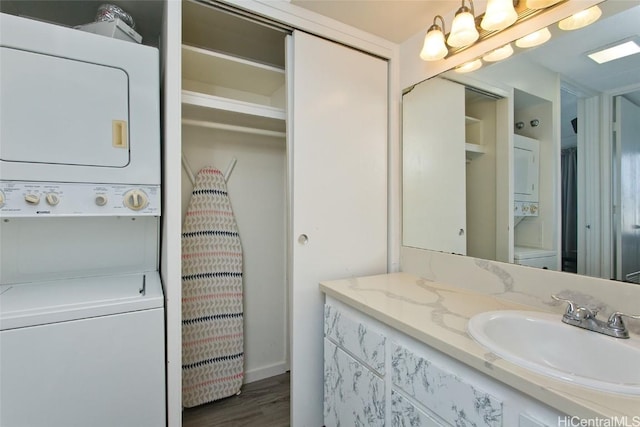 bathroom with stacked washer / dryer, wood-type flooring, a notable chandelier, and vanity