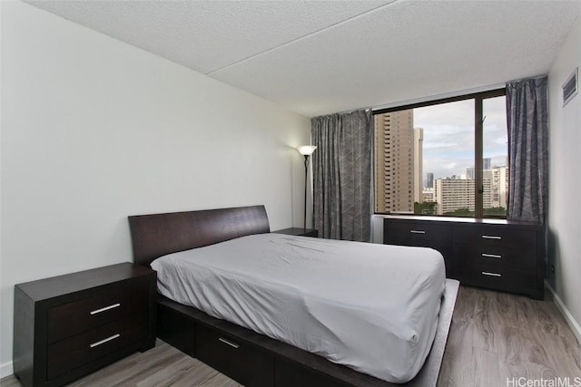 bedroom with a textured ceiling and light wood-type flooring