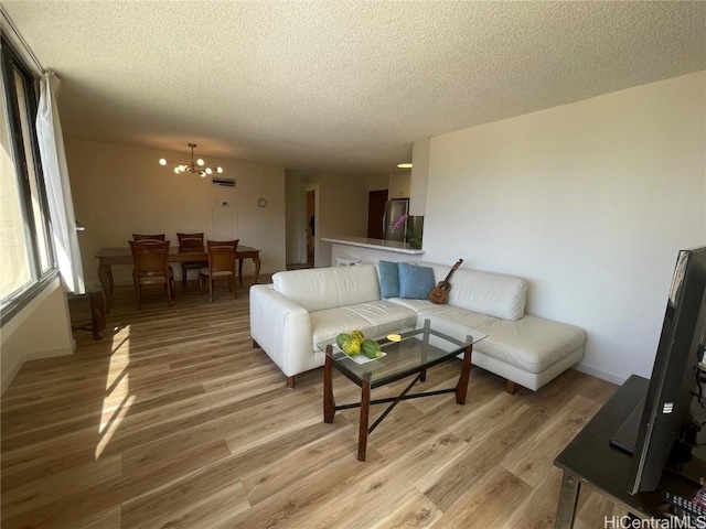 living room featuring a chandelier, a textured ceiling, and light hardwood / wood-style floors