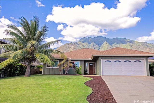 ranch-style house with a mountain view, a garage, and a front lawn