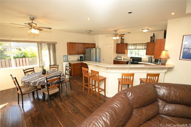 kitchen featuring kitchen peninsula, a breakfast bar, stainless steel refrigerator, and a wealth of natural light