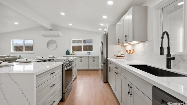 kitchen featuring light stone counters, lofted ceiling with beams, white cabinetry, appliances with stainless steel finishes, and a wall mounted air conditioner