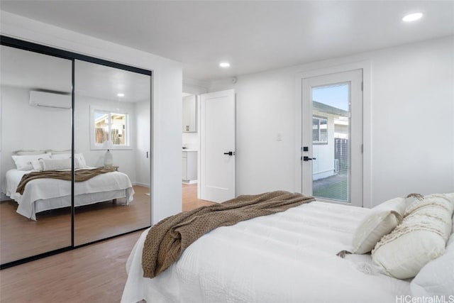 bedroom featuring access to exterior, a closet, light hardwood / wood-style floors, and a wall mounted AC