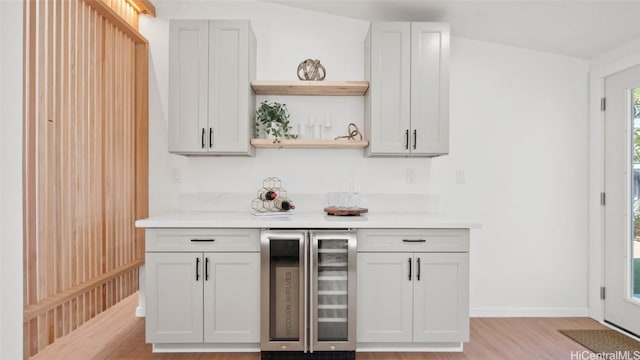 bar with white cabinets, wine cooler, and light hardwood / wood-style flooring