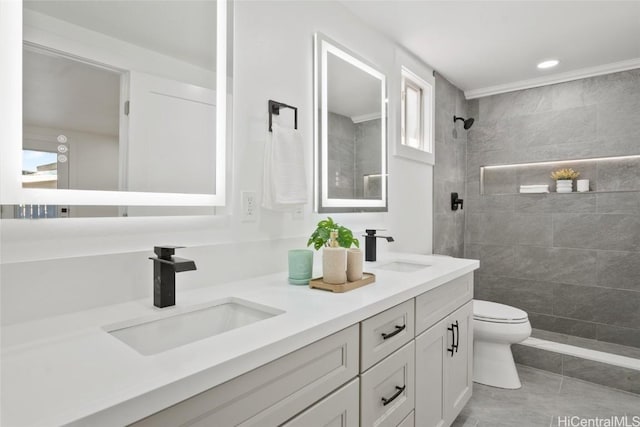 bathroom with toilet, tiled shower, and vanity