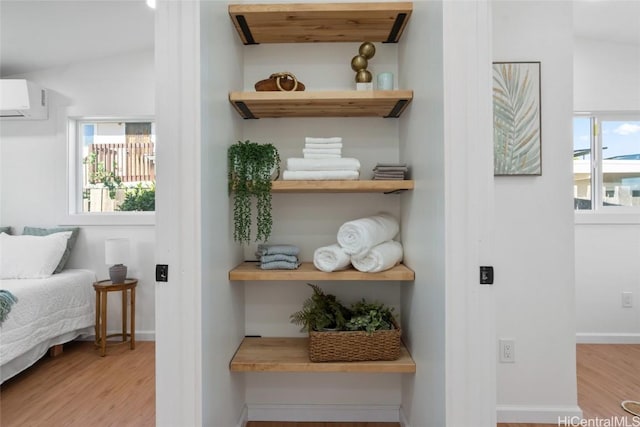 interior space with an AC wall unit, multiple windows, and light hardwood / wood-style floors