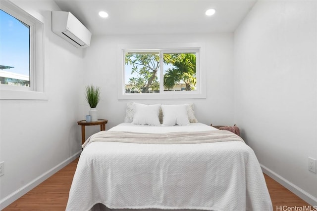 bedroom featuring wood-type flooring, an AC wall unit, and multiple windows