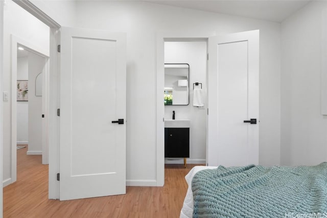 bedroom with sink, connected bathroom, and light hardwood / wood-style floors