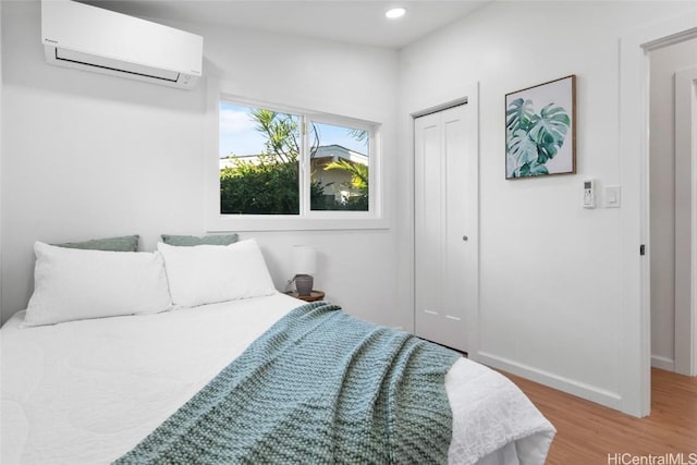 bedroom featuring light wood-type flooring, a closet, and a wall unit AC