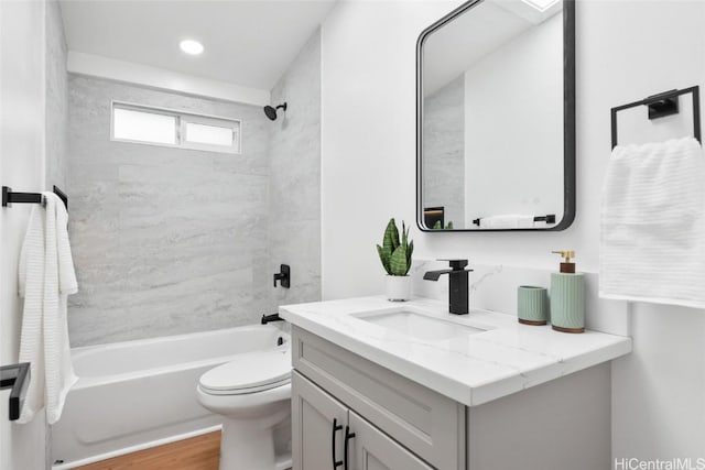 full bathroom with toilet, hardwood / wood-style flooring, tiled shower / bath, and vanity