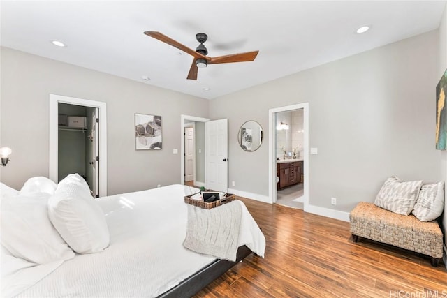 bedroom featuring ceiling fan, wood-type flooring, a spacious closet, connected bathroom, and a closet