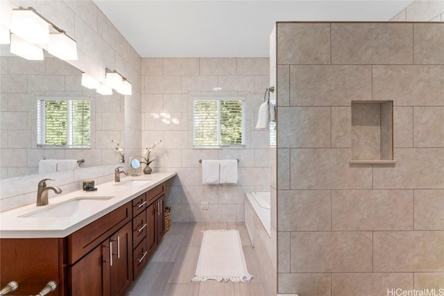 bathroom with vanity, a bathtub, tile patterned floors, and tile walls