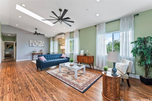 living room featuring a wall unit AC, ceiling fan, hardwood / wood-style floors, and vaulted ceiling with skylight