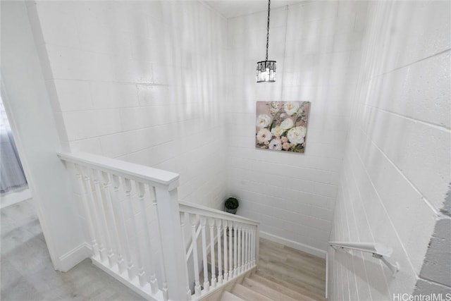 staircase featuring an inviting chandelier and hardwood / wood-style flooring