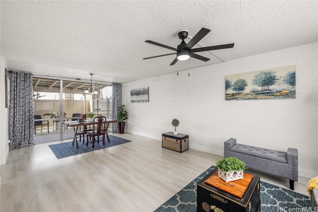 living room with hardwood / wood-style floors, ceiling fan with notable chandelier, and a textured ceiling