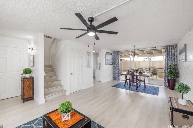 living room featuring ceiling fan, light hardwood / wood-style flooring, and a textured ceiling