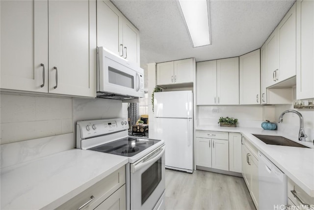 kitchen with sink, a textured ceiling, white appliances, white cabinets, and light wood-type flooring