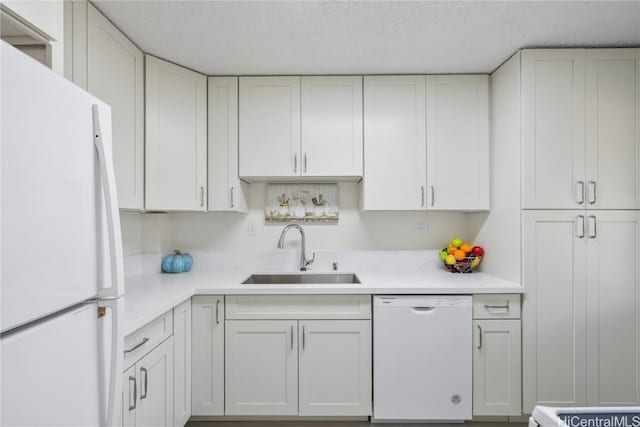 kitchen featuring white cabinets, a textured ceiling, white appliances, and sink