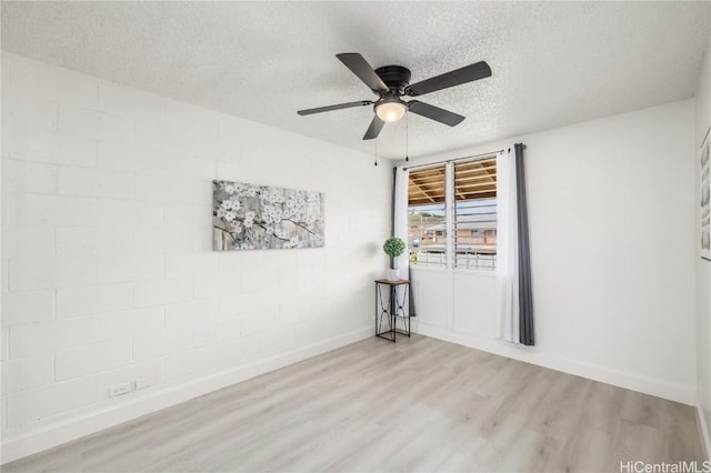 empty room featuring ceiling fan, light hardwood / wood-style flooring, and a textured ceiling