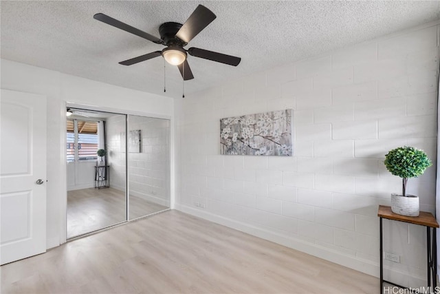 unfurnished bedroom with a textured ceiling, a closet, ceiling fan, and light hardwood / wood-style floors