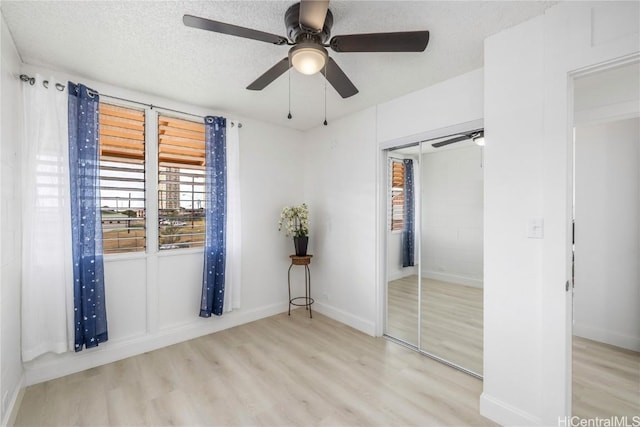 unfurnished bedroom featuring ceiling fan, a closet, a textured ceiling, and light hardwood / wood-style flooring