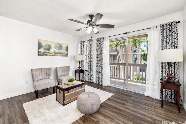 living area with ceiling fan, dark hardwood / wood-style floors, and a textured ceiling