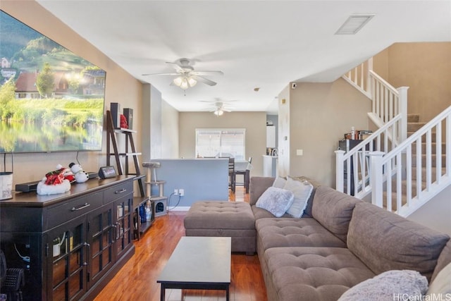 living room featuring visible vents, a ceiling fan, wood finished floors, and stairs