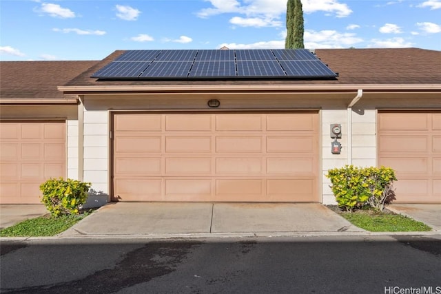 view of front of house featuring a garage, solar panels, and a shingled roof