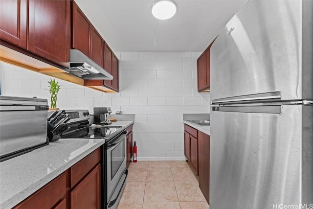 kitchen with light stone countertops, light tile patterned floors, and appliances with stainless steel finishes