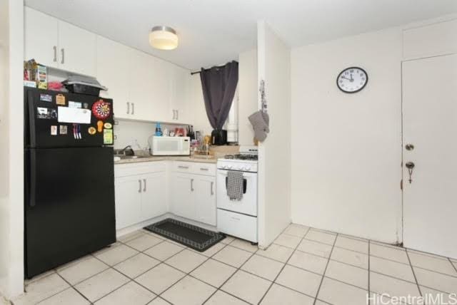 kitchen with white appliances, white cabinets, and light tile patterned flooring