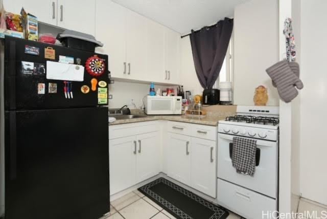 kitchen featuring light tile patterned floors, sink, white cabinets, and white appliances