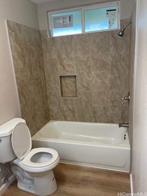 bathroom with hardwood / wood-style floors, toilet, and tiled shower / bath