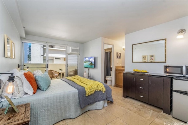 bedroom featuring ensuite bath, light tile patterned floors, and stainless steel refrigerator