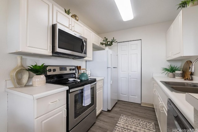 kitchen featuring appliances with stainless steel finishes, white cabinetry, and sink