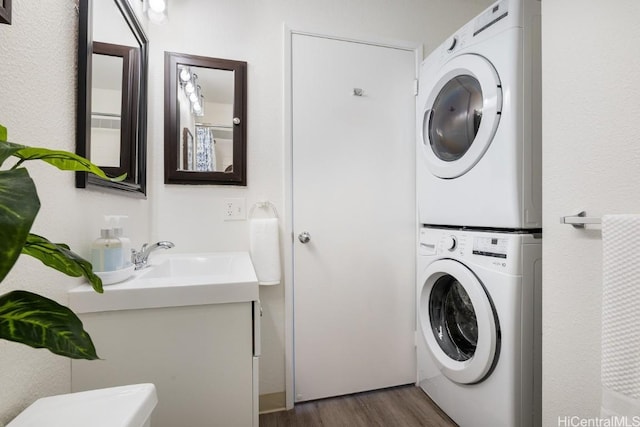 washroom with stacked washer / drying machine, dark hardwood / wood-style floors, and sink