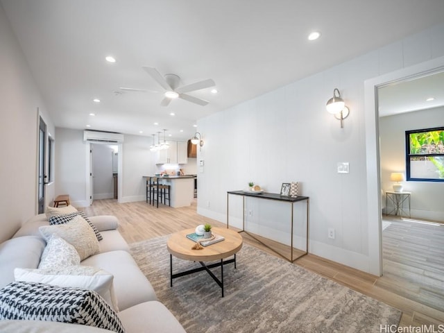 living room featuring a wall mounted AC, ceiling fan, and light hardwood / wood-style flooring